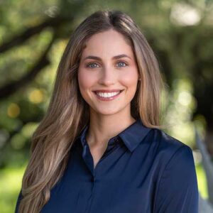 Photo of Emily Bell - a smiling woman with long hair in front of a backdrop of trees in soft focus