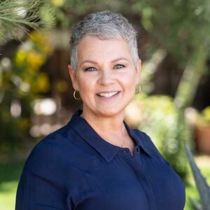 Photo of Jana Starner - a smiling woman with short hair in front of a backdrop of trees in soft focus